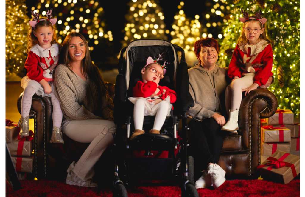 photo of claire house family sitting and smiling, surrounded by christmas decorations and lights