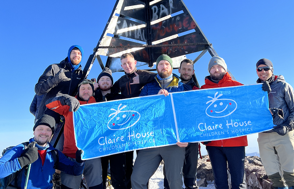 nine people after completing a trek holding a claire house banner